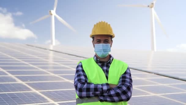 コロナウイルス発生時にフェイスマスクを着用しながら 風力タービンや太陽光パネルで代替エネルギーのために働く若いエンジニア 革新と緑の電力コンセプト — ストック動画