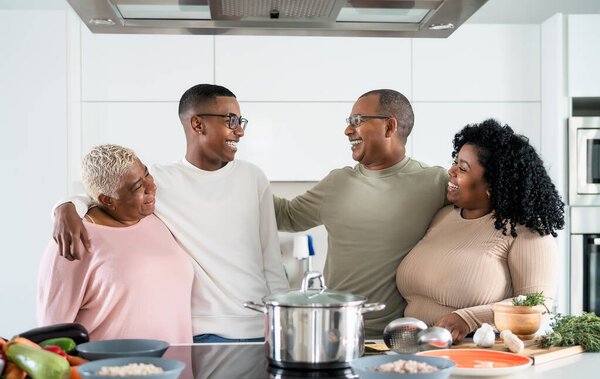 Happy black family having fun cooking together in modern kitchen - Food and parents unity concept