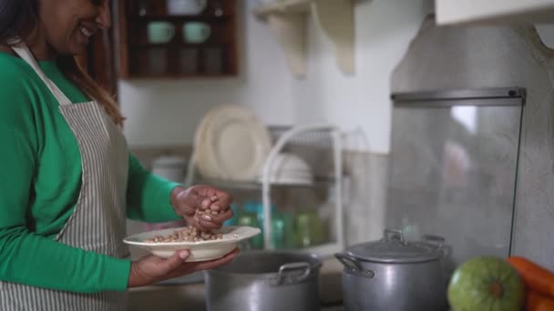 幸せな成熟した女性料理で古いヴィンテージキッチン-ラテン女性準備豆スープに家 — ストック動画