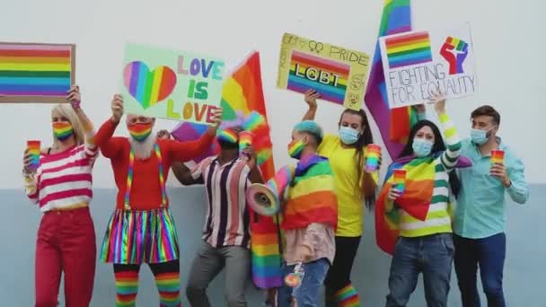 Oameni multirasiali fericiți care poartă mască de față sărbătorind la festivalul de mândrie gay în timpul virusului corona - Grup de prieteni cu diferite vârste și rase dansând împreună și luptând pentru egalitatea de gen — Videoclip de stoc