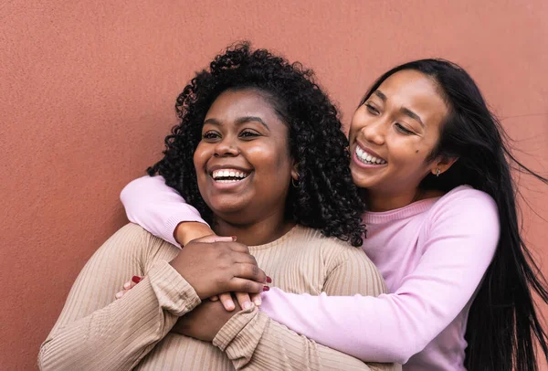 Meninas Latinas Felizes Divertindo Abraçando Enquanto Está Contra Parede Vermelha — Fotografia de Stock