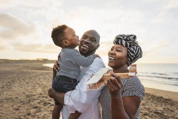 Happy African family having fun on the beach during summer vacation - Parents love and unity concept