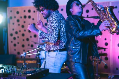 Genç mutlu insanlar DJ mikser ve saksafon ile ev stüdyosunda müzik çalıyorlar - genç müzisyen eğlence konsepti