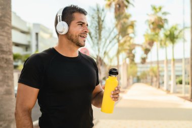 Latin adam, dışarıda kablosuz kulaklıkla müzik dinlerken koşu ve egzersiz yapıyor.