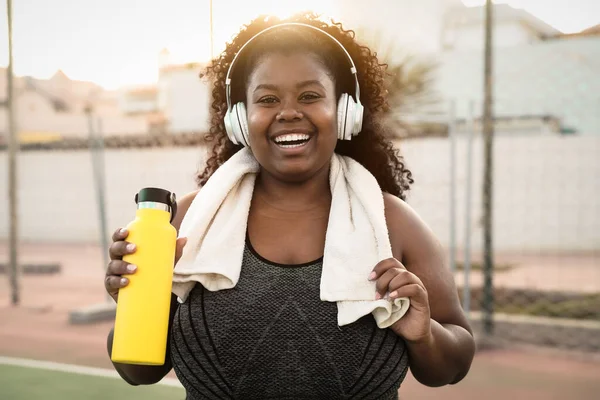 ハッピーカービーアフリカの女性は無線ヘッドフォン屋外で音楽を聞きながらジョギングやワークアウトルーチンを行う — ストック写真