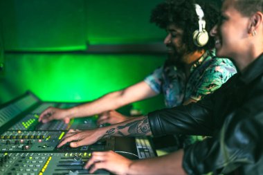 Gençler müzik stüdyosunda panel kontrolüyle birlikte çalışıyorlar.