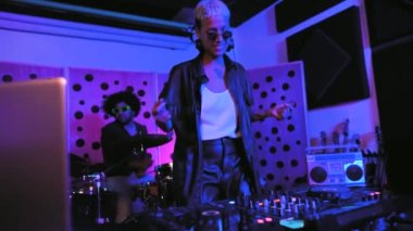 Genç mutlu insanlar DJ mikser ve davul ile ev stüdyosunda müzik çalıyorlar.