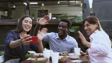 Yemek kamyonunda yemek yerken cep telefonuyla video görüşmesi yapan mutlu insanlar.  