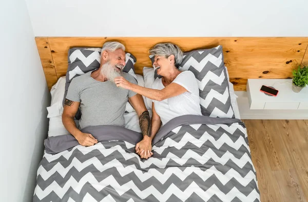 Szczęśliwa Para Seniorów Śmiejących Się Razem Leżąc Łóżku Pod Kocami — Zdjęcie stockowe