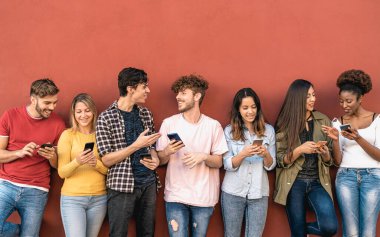 Genç arkadaşlar açık havada cep telefonu kullanıyor - Milenyum jenerasyonu yeni eğilimlerle eğleniyor sosyal medya uygulamaları - gençlik teknolojisi bağımlıları - kırmızı arka plan