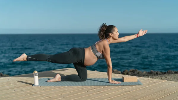 妊娠中の若い女性は 海の横に出生前のピラティス演習セッションを行う 健康ライフスタイルと妊産婦の概念 — ストック写真