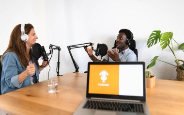 Çok ırklı insanlar, stüdyodaki mikrofon ve dizüstü bilgisayarla bir podcast kaydediyor.