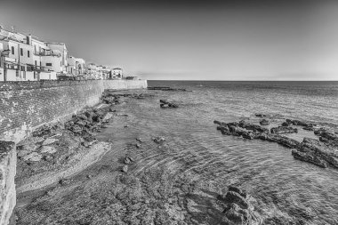 İtalya 'nın kuzeybatısındaki Sardunya' nın ünlü merkezi ve tatil beldesi Alghero 'nun en önemli manzaralarından biri olan tarihi surların üzerinde gün batımında manzara.