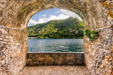Moorea, Fransız Polinezyası 'ndaki tropik bir plaja bakan manzaralı kaya kemer balkonu.