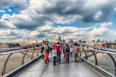 LONDON - 15 Nisan 2022: Millennium Köprüsü üzerinde yürümek, Londra, İngiltere 'de Thames Nehri' ni geçen yayalar için çelik asma köprüsü