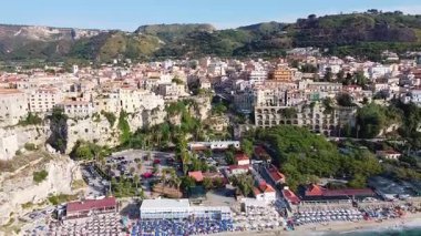 Hava manzarasında Tropea 'nın turkuvaz suları, kalabalık bir kumlu plaj ve dramatik uçurumların tepesine tünemiş binalar yer alıyor. Calabria 'daki büyüleyici İtalyan tatil köyü görünüyor..