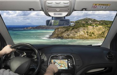 Bu görüntü bir sürücünün manzaralı sahil yolunda giden bir arabadan bakış açısını yakalar. Sergide engebeli kayalıklar, derin mavi bir deniz, uzak dağlar ve berrak bir gökyüzü yer alıyor..