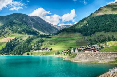 Turkuaz su, İtalya 'nın Trentino Alto Adige kentindeki Vernago Gölü' nde güneşli bir yaz gününün mavi gökyüzünü yansıtıyor.