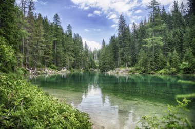 Braies Gölü 'nün ikonik manzarası turkuaz sularıyla Dolomitler, Güney Tyrol, İtalya' da dağlar ve ormanlarla çevrili.