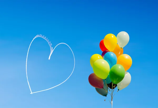 Bunte Luftballons und Herzen mit Flugzeugen in den Himmel geschrieben — Stockfoto