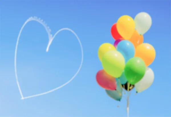 Fondo desenfocado de globos y corazón escrito en el cielo — Foto de Stock