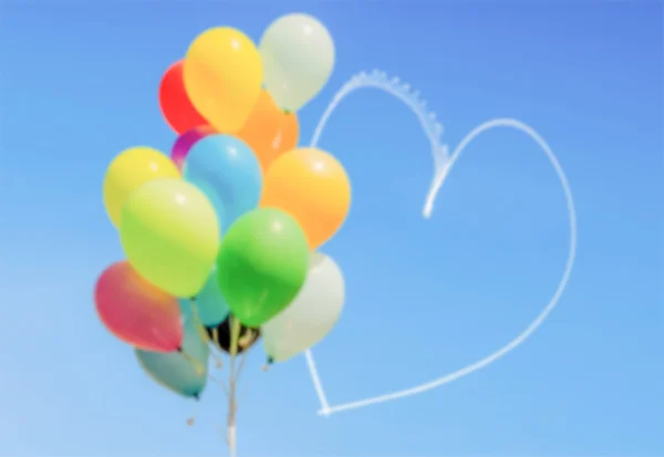 Defocused background of balloons and heart written in the sky — Stock Photo, Image