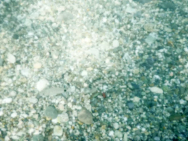 Defocused background of underwater pebbles at the seaside — Stock Photo, Image