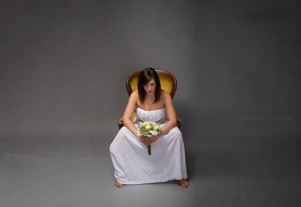 Unhappy bride sitting with bouquet — Stock Photo, Image