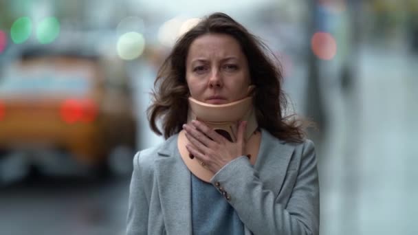 Sad woman with neck ache is walking on city street, wearing orthopedic collar, curing of osteochondrosis — Stock Footage Sad woman with neck ache is walking on city street, wearing orthopedic collar, curing of osteochondrosis Stock Footage