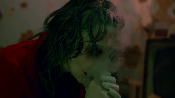 Horror bohóc nő dohányzik egy komor szobában sminkkel az arcán