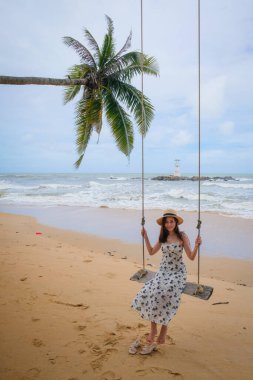 Tayland 'ın Phang Nga eyaletindeki Khao lak deniz fenerinde Nang Tanga Sahili' nin arka bahçesinde sallanan güzel bir kız. Güzel kayalar var seyrek, yumuşak beyaz kum.