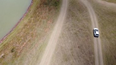4K, Aerial View 'da, kırsal kesimde doğanın doğasını takip eden beyaz arabayı takip ediyor..