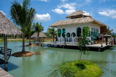 Çevresi kıyı ve ağaçla çevrili tropik kahve dükkanı.