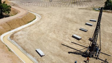 Yığınla ekipman toprağa kazık dikmek için güneş çiftliği için hazırlık, temel inşaatında direklerin çalışması için ağır makineler. İHA 'dan havadan görüntüleme yüksekliği.