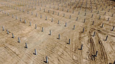 Yığınla ekipman toprağa kazık dikmek için güneş çiftliği için hazırlık, temel inşaatında direklerin çalışması için ağır makineler. İHA 'dan havadan görüntüleme yüksekliği.