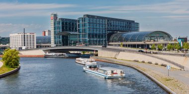 Berlin, Almanya - 10 Temmuz 2011: Berlin Hauptbahnhof Spree Nehri üzerinde. Berlin Merkez Tren İstasyonu 'nda parlak bir yaz gününde tur tekneleri açılır..