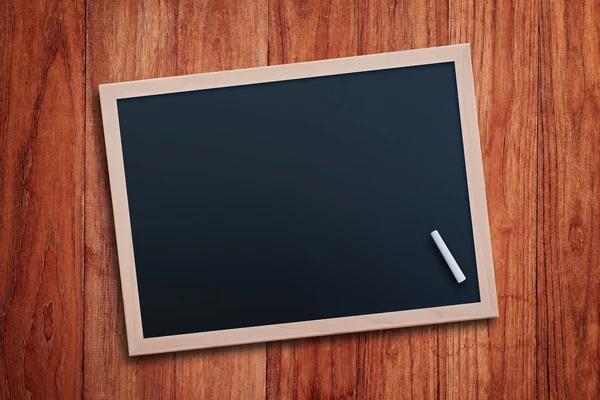 Black chalkboard on wood table — Stock Photo, Image