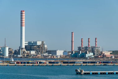Coal-fired power plant with tall smokestacks in the port of Civitavecchia, Italy.