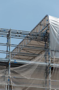 İşçileri güneş ışınları ve sıcaktan korumak için bir inşaat alanının çatısında iskele var. Roma, İtalya..