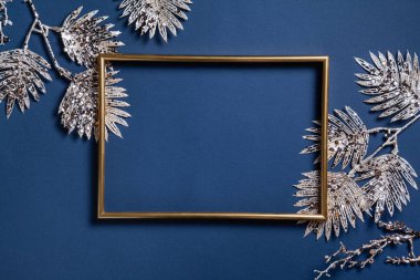Noel kompozisyonu. Mavi arka planda altın dalları olan bir çerçeve. Noel, kış, yeni yıl konsepti. Düz konum, üst görünüm, kopyalama alanı.