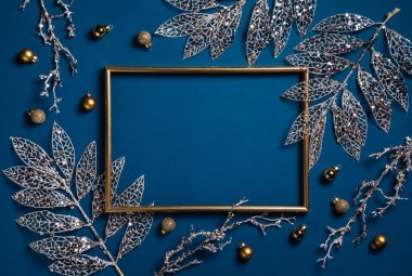 Noel kompozisyonu. Mavi arka planda altın dalları olan bir çerçeve. Noel, kış, yeni yıl konsepti. Düz konum, üst görünüm, kopyalama alanı.