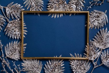 Noel kompozisyonu. Mavi arka planda altın dalları olan bir çerçeve. Noel, kış, yeni yıl konsepti. Düz konum, üst görünüm, kopyalama alanı.