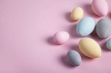 Mutlu Paskalyalar. Renkli paskalya yumurtaları pastel pembe arka planda boyanmış. Düz konum, üst görünüm, kopyalama alanı.