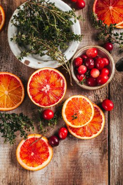 Turunçgil ve çilek çayı yapmak için gerekli malzemeler. Yaban mersini, kan portakalı ve kekik ahşap masada. Üst Manzara. Düz yatıyordu.