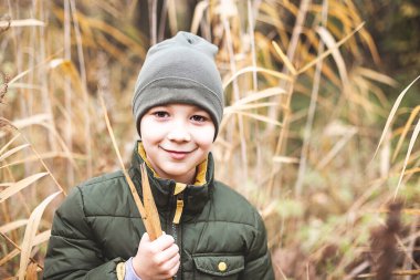 Mutlu çocuk sonbahar ormanında yürüyor. Seçici odak. 