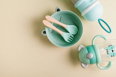 Bebek beslenme aksesuarları. Bir tabak, bir kaşık, bir çatal, süt şişesi ve süt formülü depolamak için bir kavanoz. Düz konum, üst görünüm, kopyalama alanı.