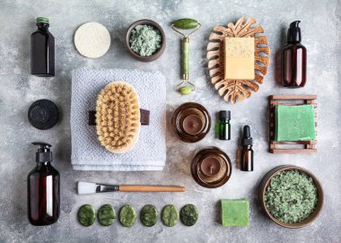 Gri arka planda doğal cilt bakım ürünleri. Masaj taşları ve fırçalar, temel yağlar, deniz tuzu ve fırça. Spa tedavisi kavramı. 