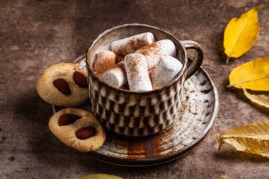 Kahverengi arka planda seramik bardak sıcak çikolata, lokum ve kurabiyeler. Sonbahar sıcak içeceği.