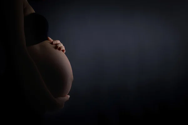 一名怀孕的妇女，爱抚着她的肚子 — 图库照片