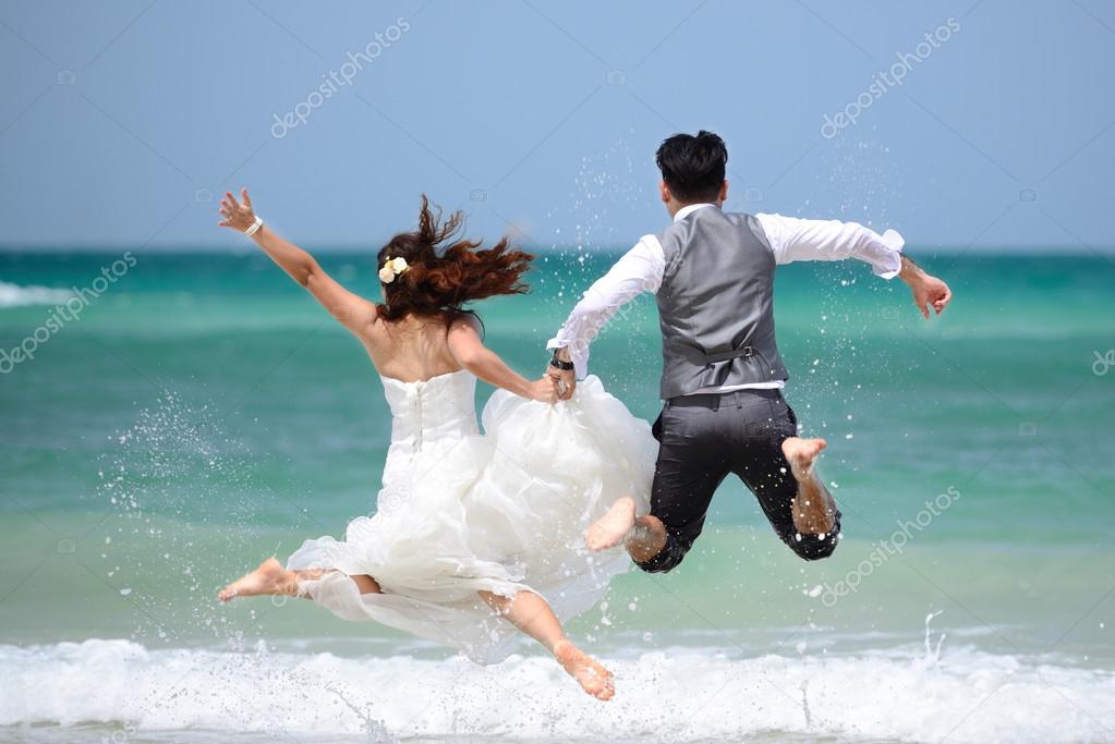 happy just married young couple celebrating and have fun at beac